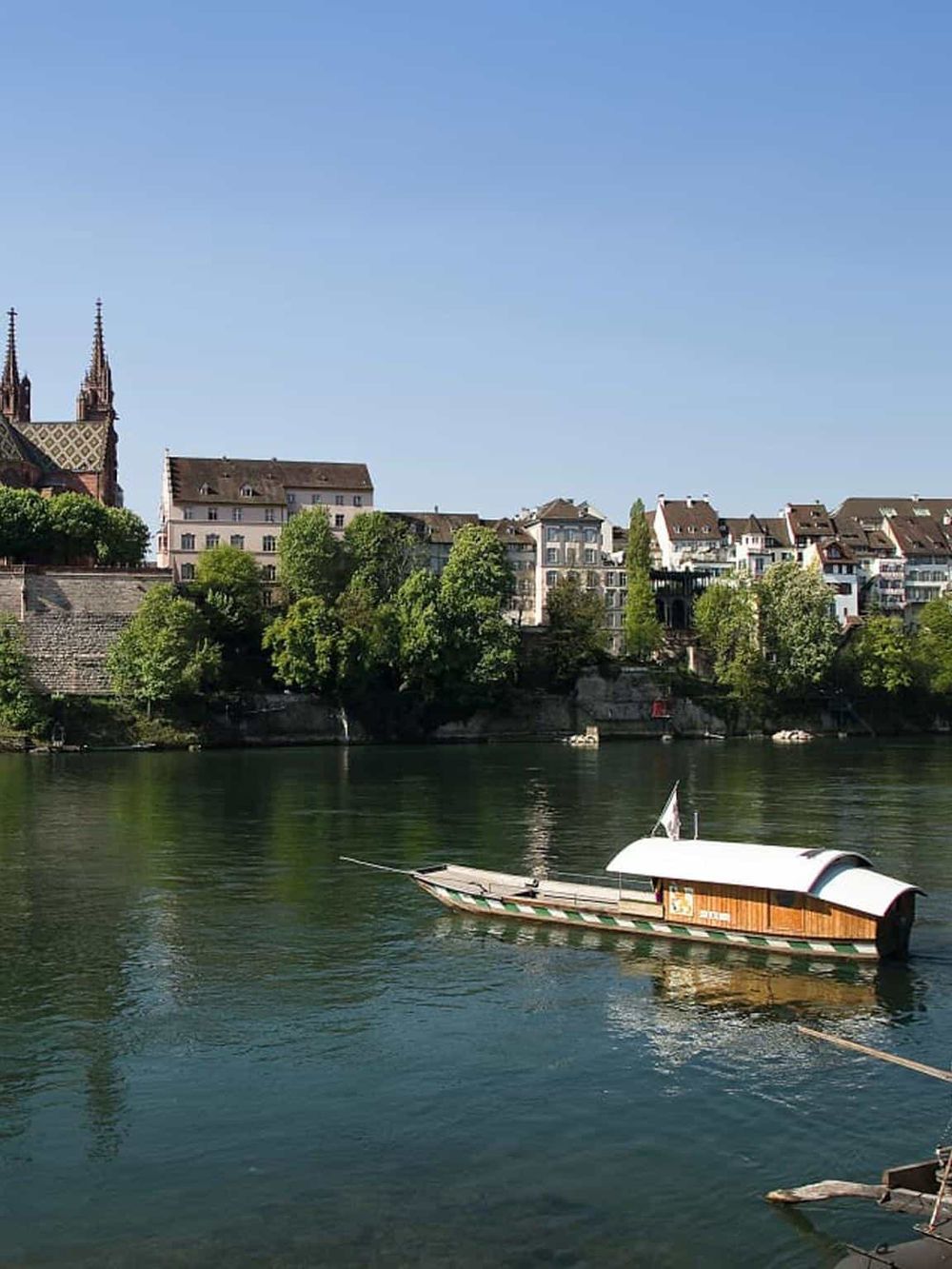 Boats on a river in a city with historic buildings and church spires in the background.