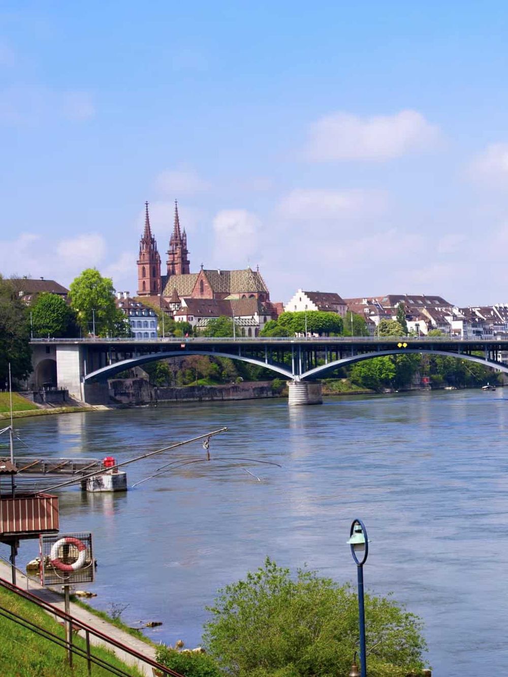 Scenic view of a river with a bridge, historic church, and cityscape in a European town, showcasing travel destinations and architecture.