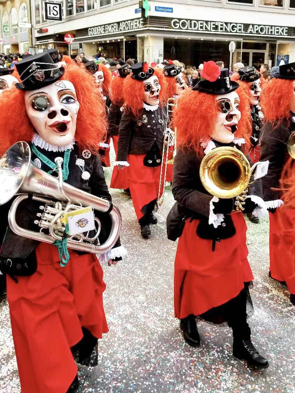 Colorful carnival parade with costumed performers and musical instruments on city street.