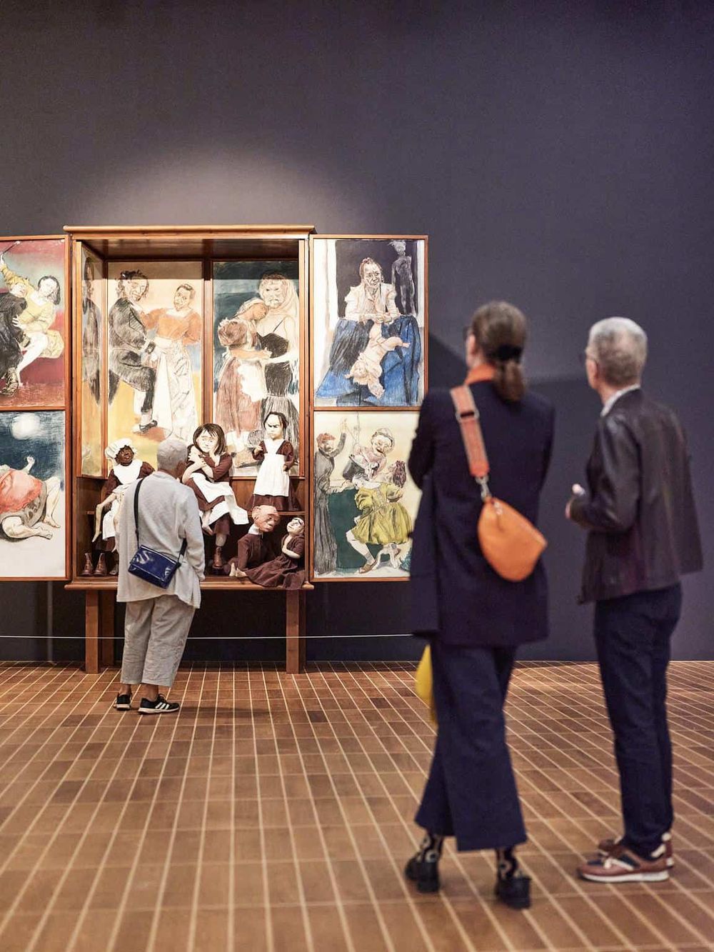 Colorful puppet art display at a museum exhibit with visitors observing.