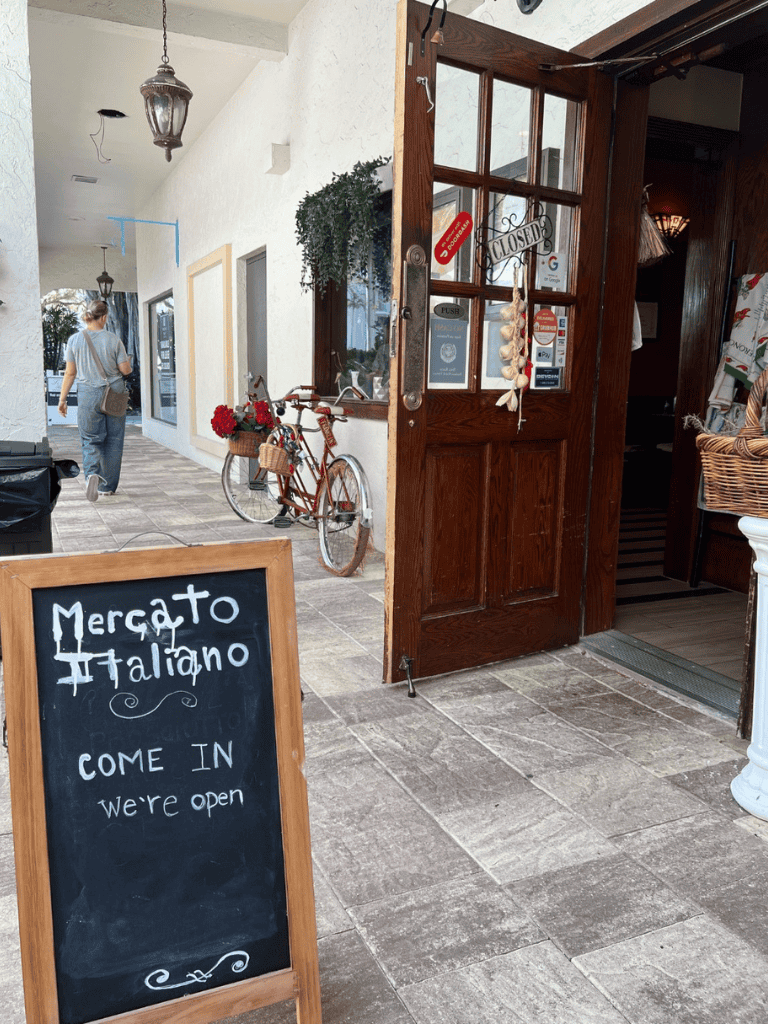 Quiet Italian restaurant entrance with "Mergato Italiano" sign and open doors.