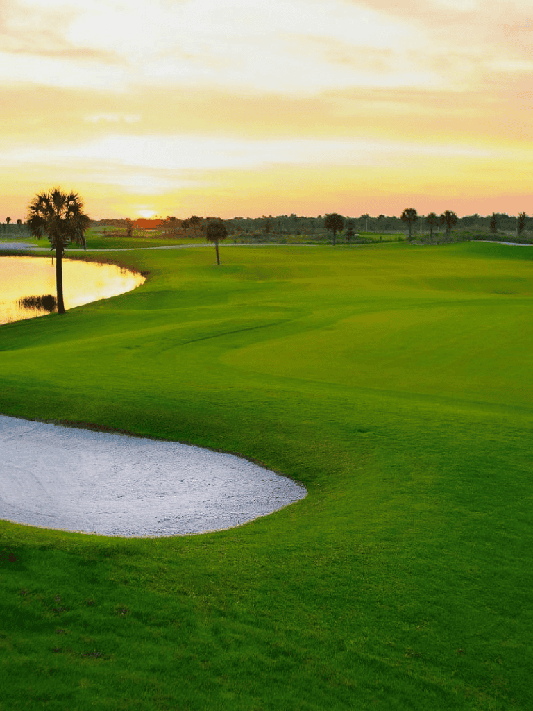 Scenic golf course at sunset with green fairways and water hazards, ideal for golf enthusiasts.