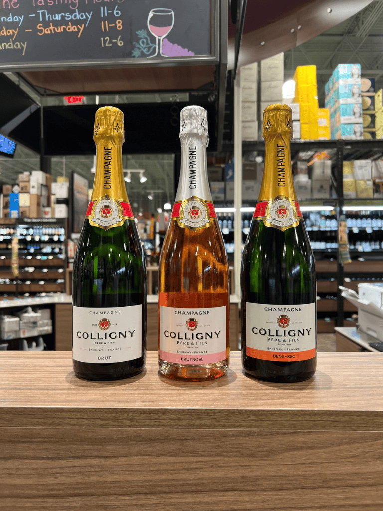 1. Bottles of Colligny Champagne in a liquor store display, including Brut, Brut Rosé, and Demi-Sec.