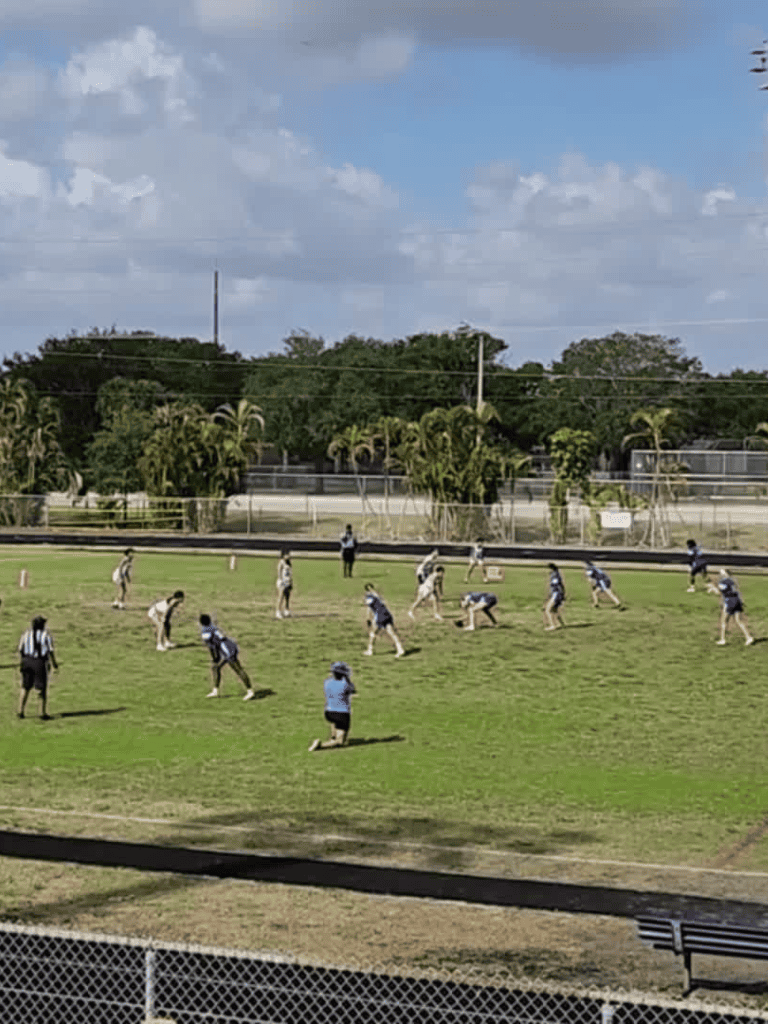 Youth football game on a grassy field with players in action under a partly cloudy sky.