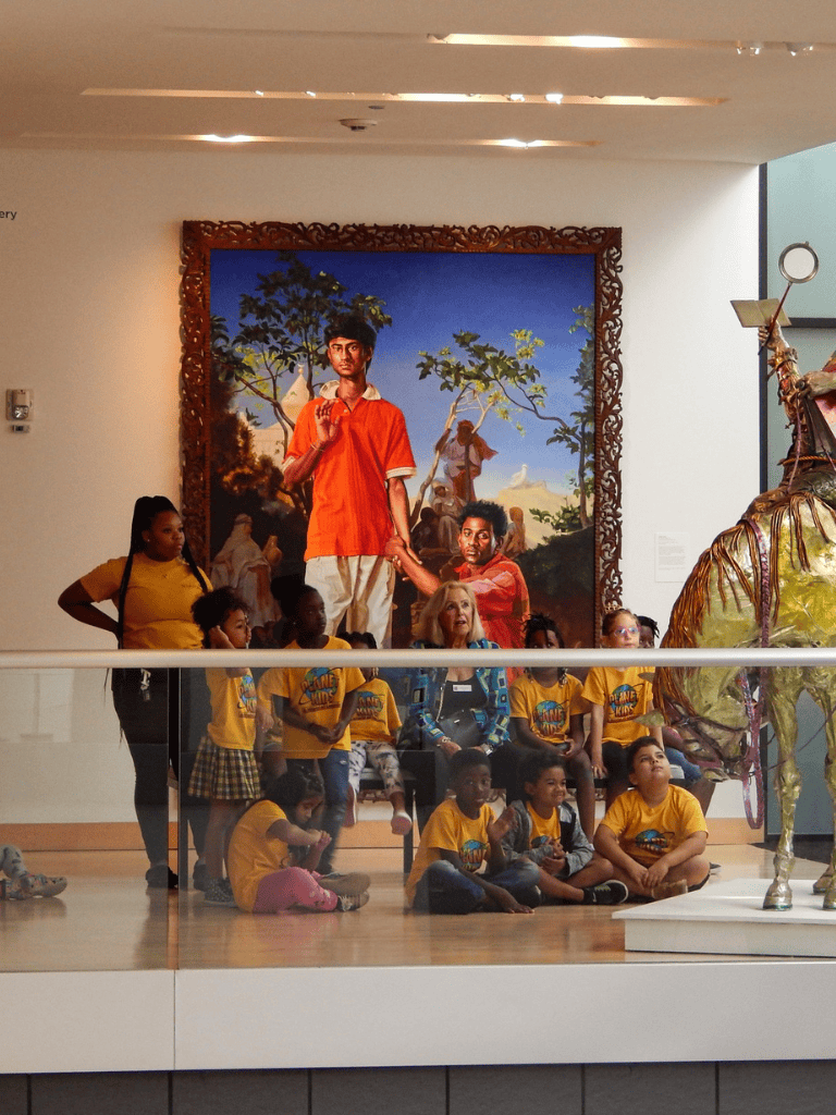 Vibrant group of children visiting an art museum, admiring a large colorful painting and sculpture exhibit.