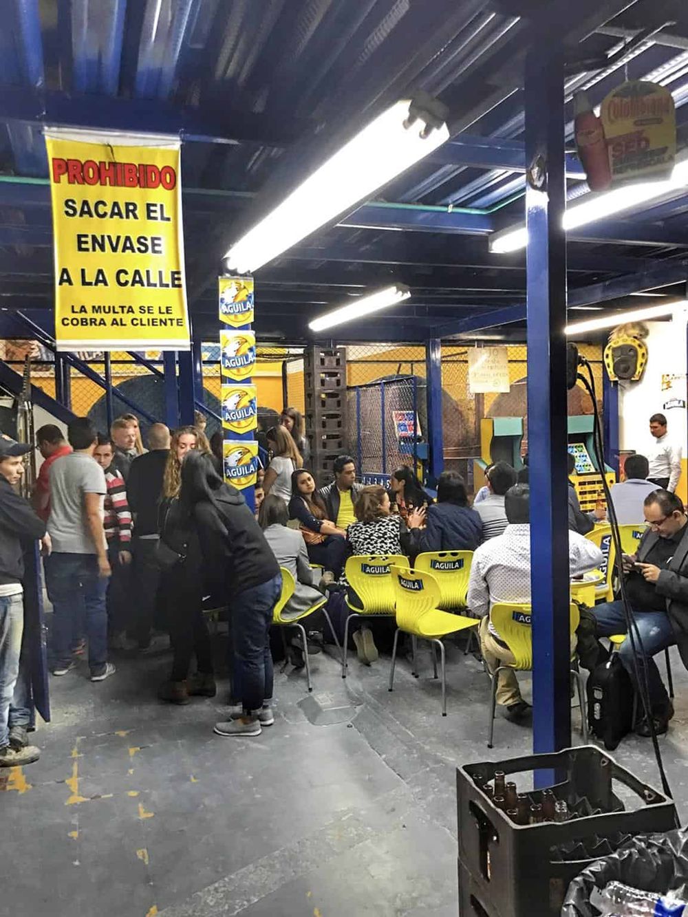 Crowd gathered at a Mexican beer venue with Azul logo, low ceilings, and bright lighting.