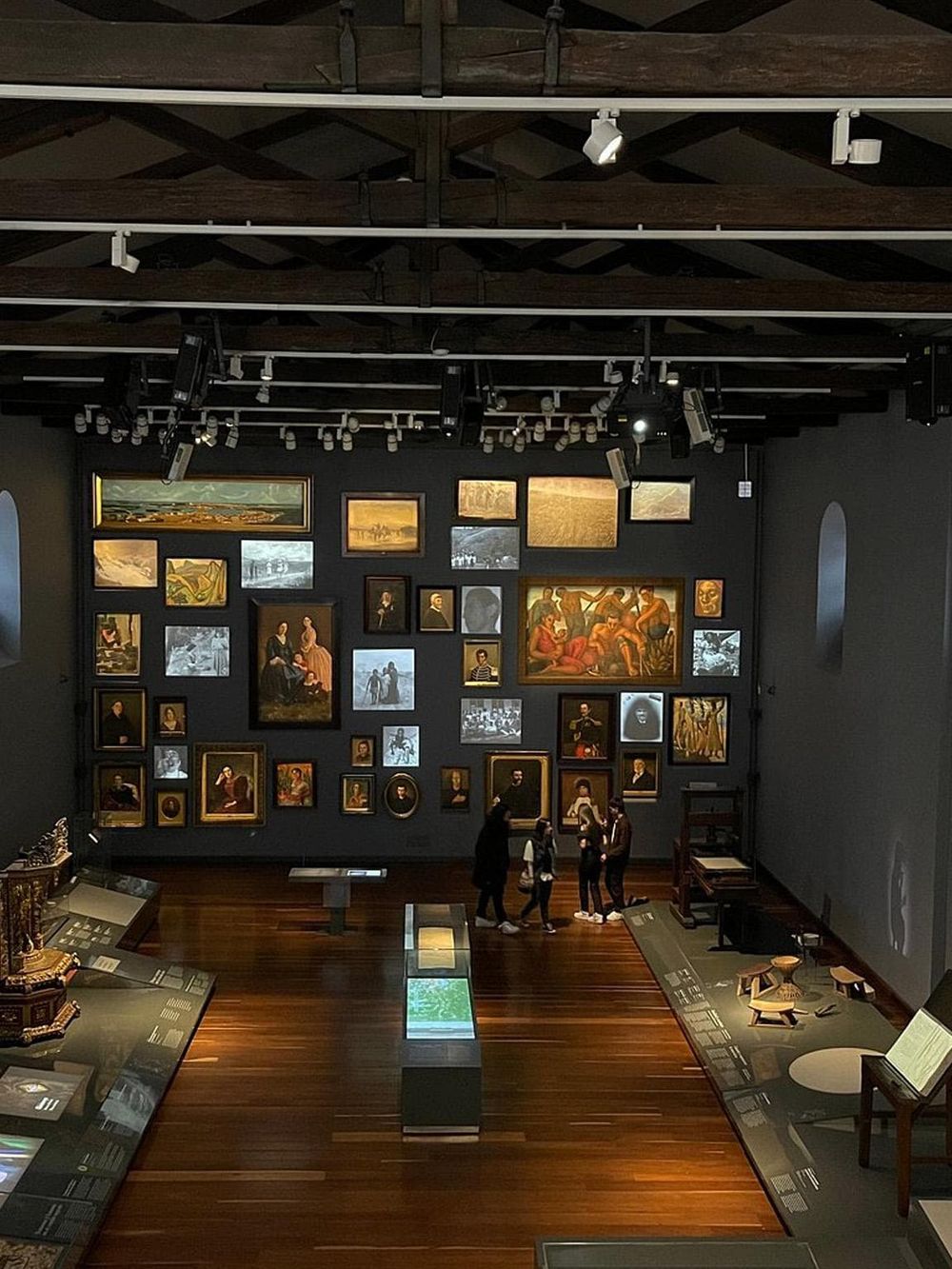 Historic art gallery exhibit showcasing classic paintings and photographs in a museum setting.