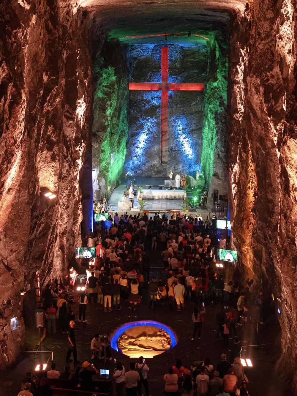 Impressive underground church with vibrant lighting and large cross at the altar.
