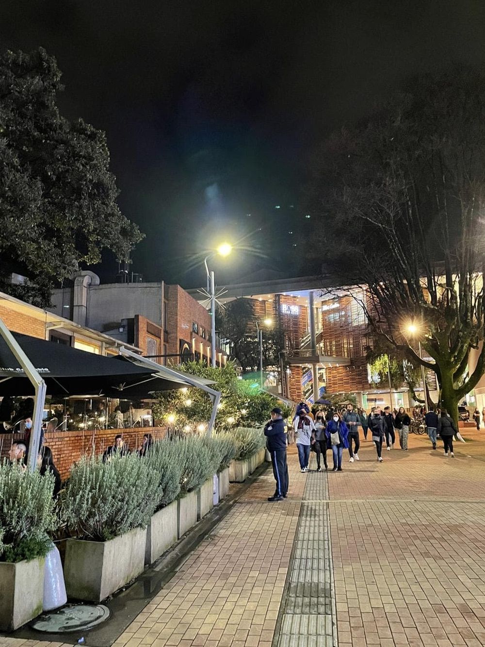 Night city street lively crowd at evening, urban scene with shops and people walking, vibrant nightlife atmosphere.