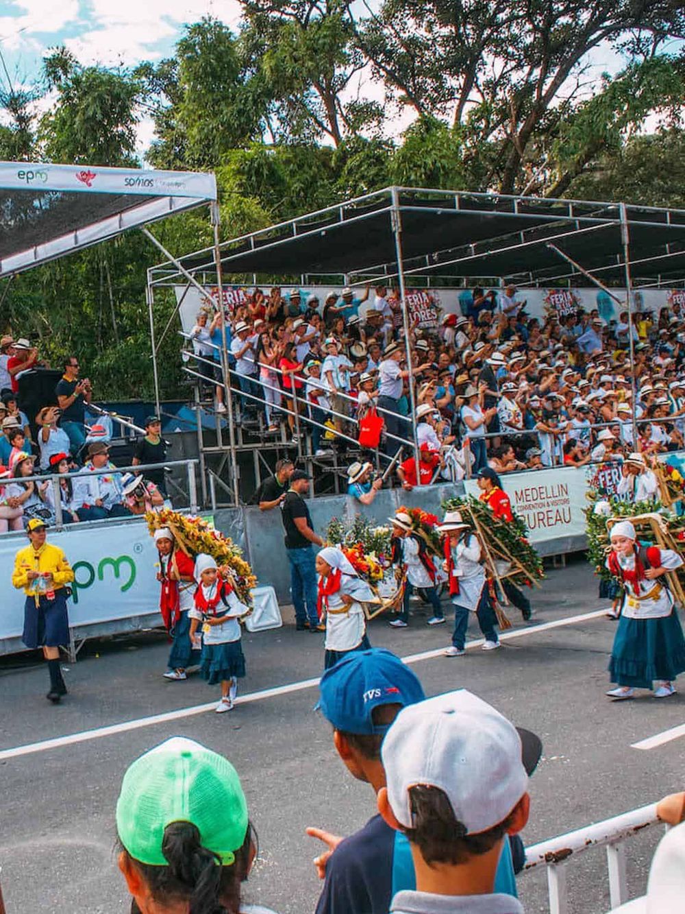 Vibrant cultural parade with traditional dancers and large crowds at a street festival, celebrating Colombian heritage.