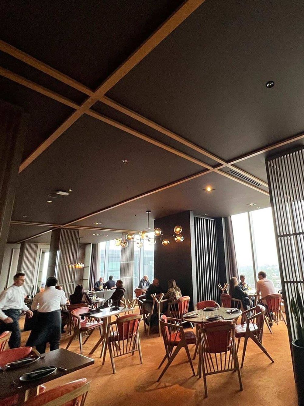 Modern upscale restaurant interior with large windows and stylish wooden accents.