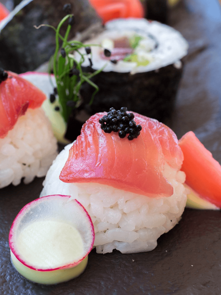 Fresh sushi featuring salmon, caviar, and wasabi on a black slate platter for Japanese cuisine lovers.