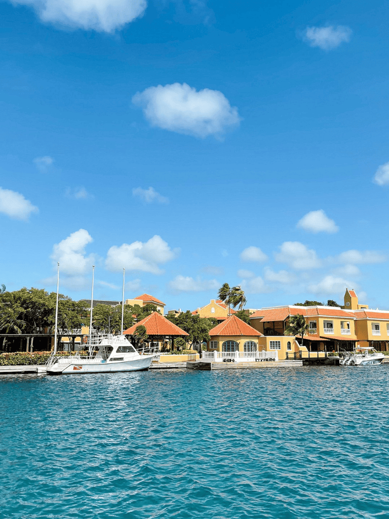 Boating waterfront view of colorful tropical houses and yachts under a bright blue sky in a coastal destination.