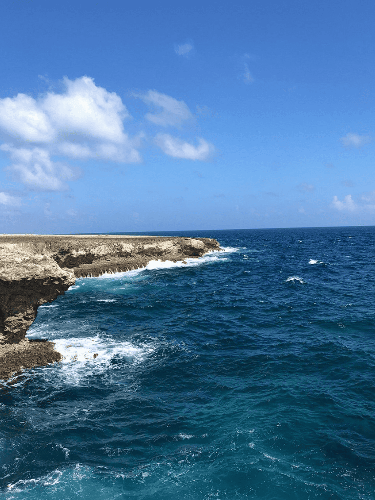 Vast ocean view with rocky coastline and blue sky, perfect for coastal navigation.