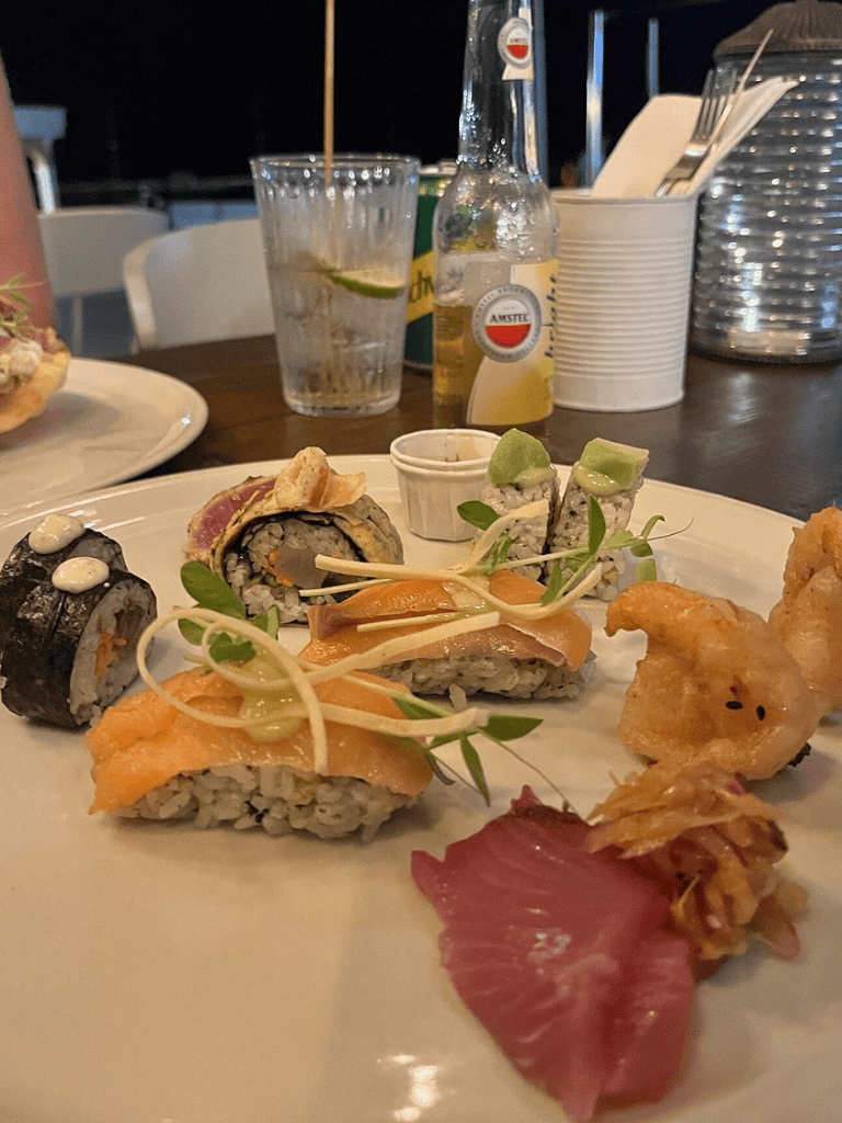 Fresh sushi platter with assorted rolls and sashimi at a coastal restaurant.