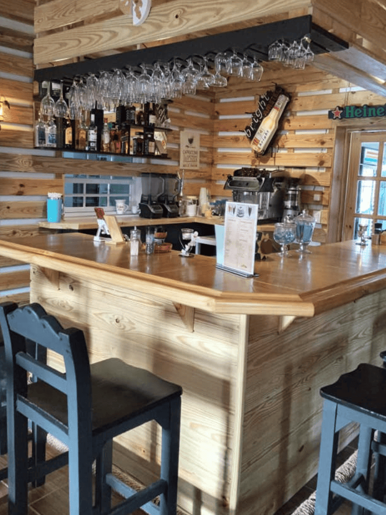 Enjoy your drink at a cozy wooden bar with hanging glassware and a full coffee station at QuestForDirections.