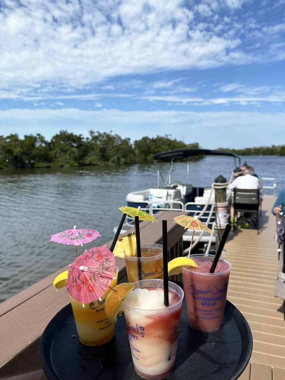 Refreshing tropical cocktails with umbrellas on a dock by the water, perfect for a scenic boat trip with QuestForDirections.