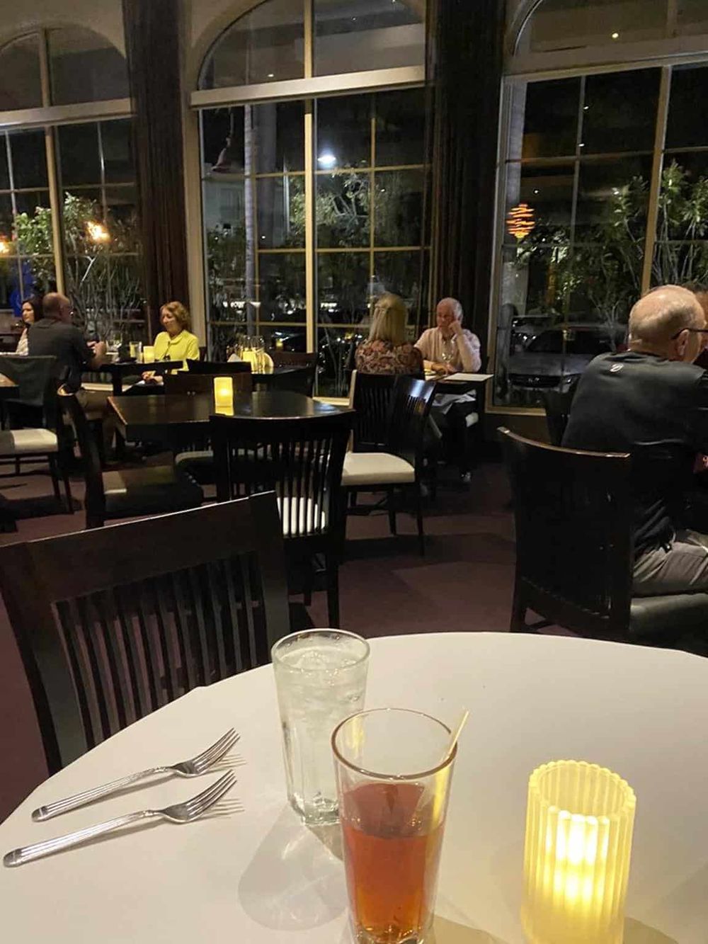 Cozy restaurant interior with large windows, dim lighting, and relaxed dining atmosphere, showcasing an inviting ambiance for dinner.