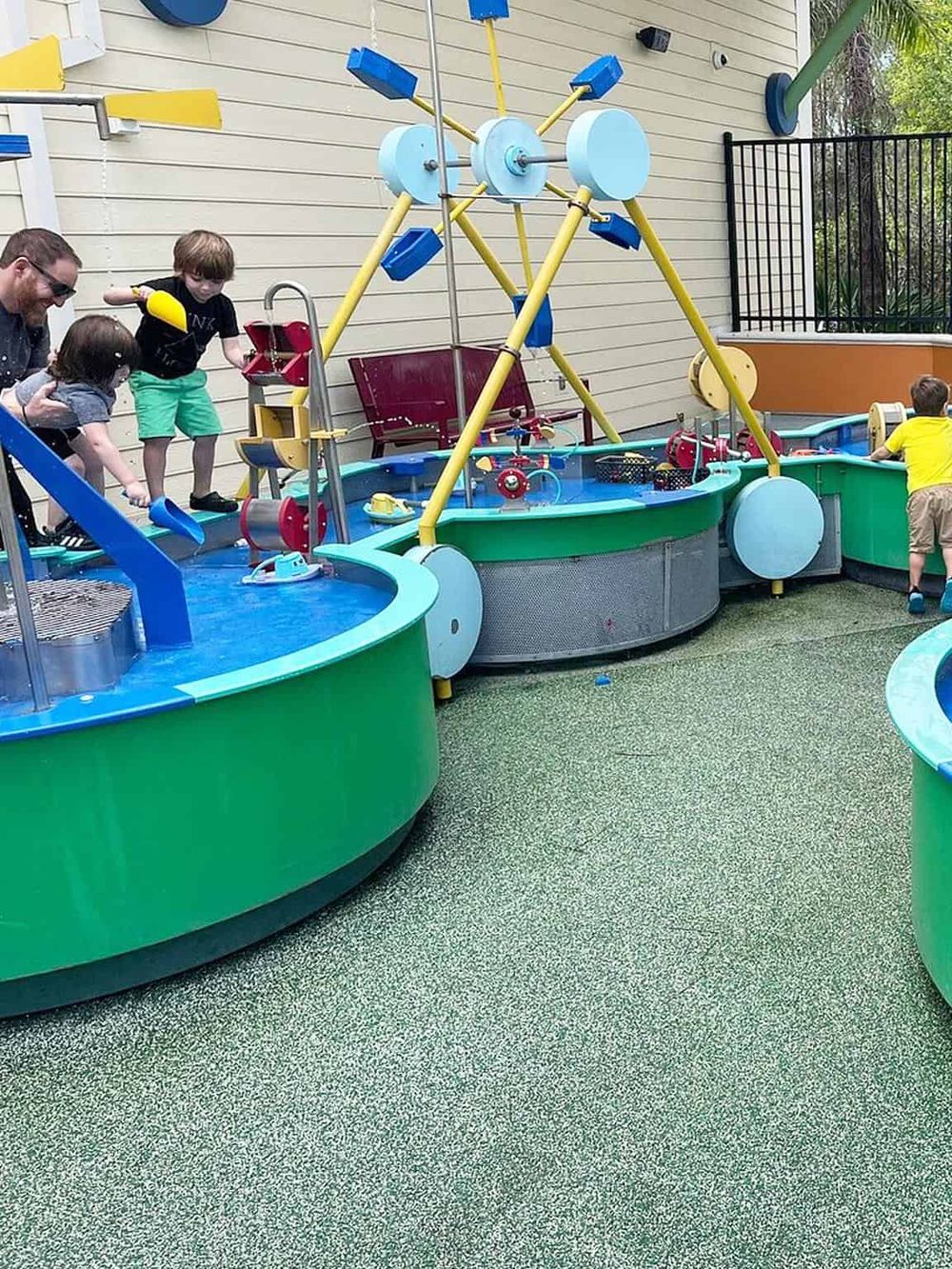Colorful outdoor play area with water features and children having fun.