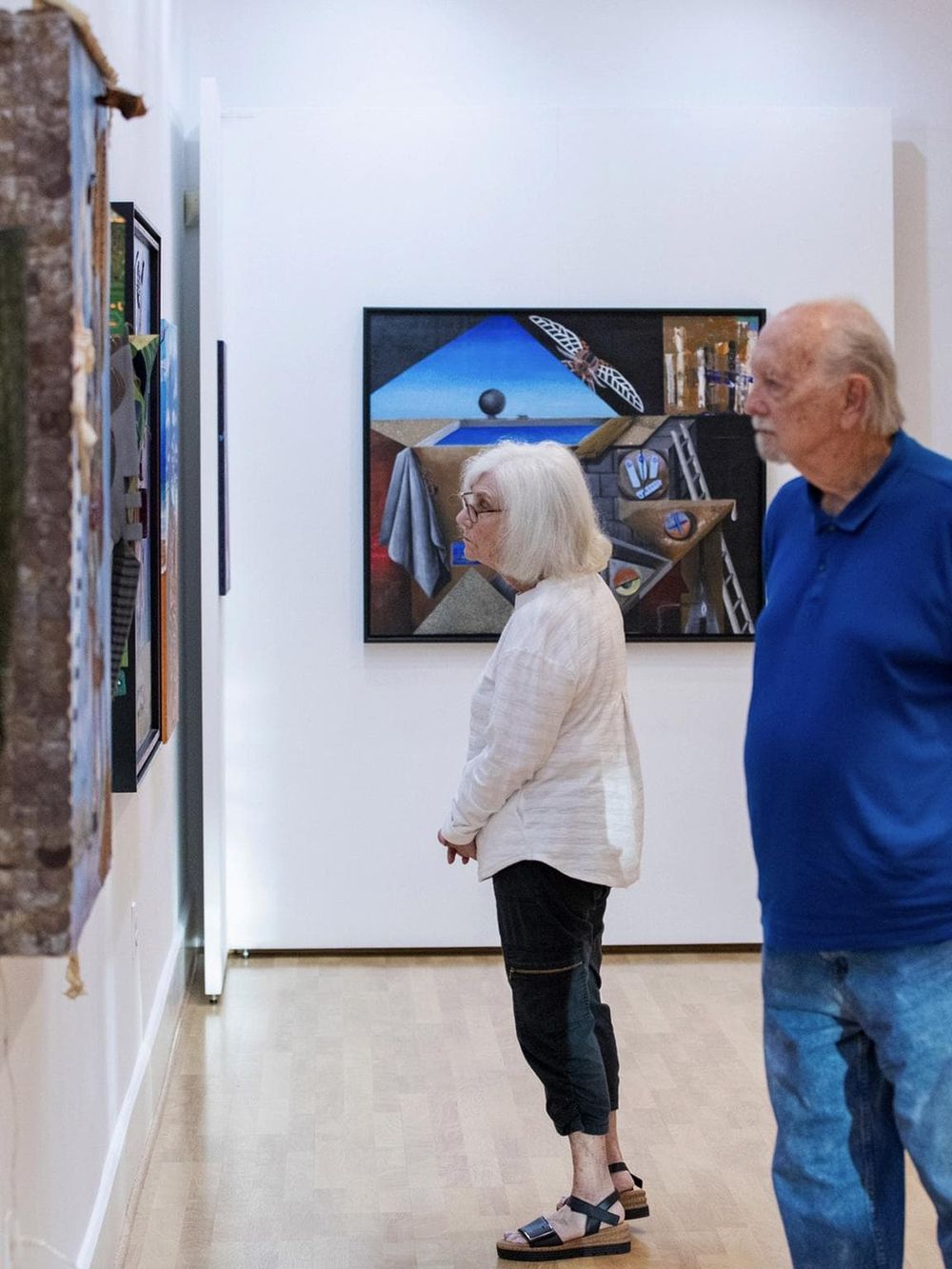 Intriguing art gallery visitors viewing contemporary paintings at QuestForDirections art exhibit.