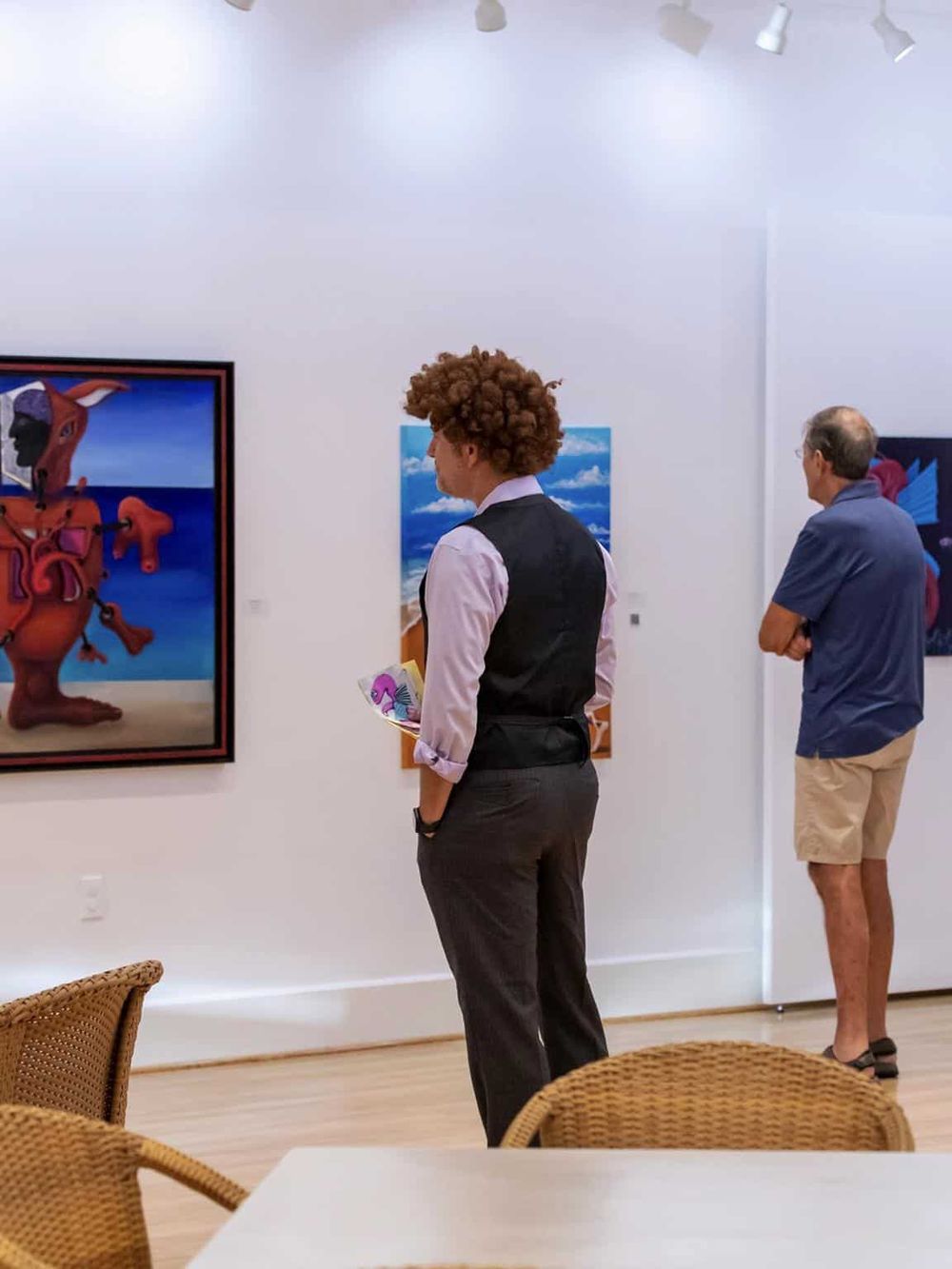 Colorful art gallery showcasing contemporary paintings and visitors engaging with artwork.