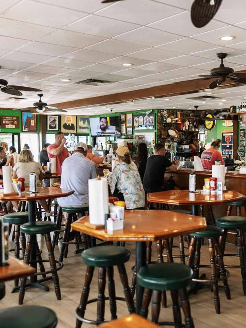 Cozy restaurant interior with patrons enjoying food, TV screens, and vibrant decor, perfect for dining and socializing.