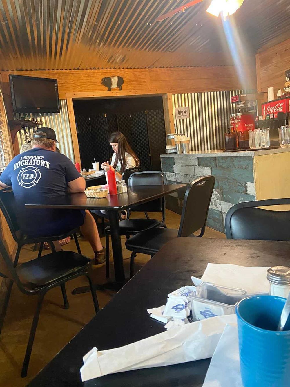 Cozy restaurant interior with wood-paneled walls, customers dining, and casual atmosphere for Quest For Directions.