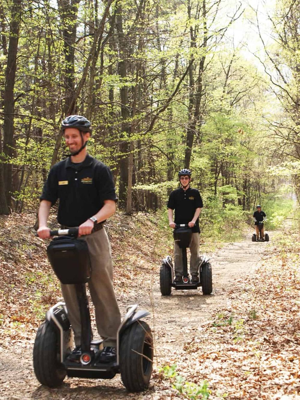 Segway tour guides exploring a wooded trail, outdoor adventure, eco-friendly transportation, forest excursion, trail riding experience.
