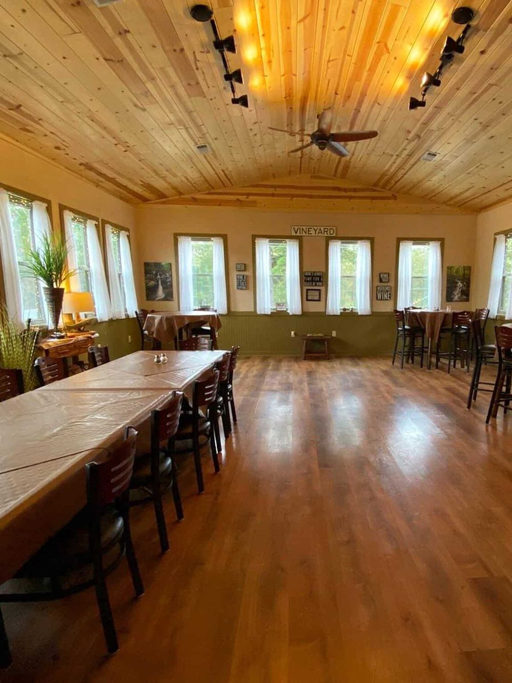 Cozy vineyard-themed event space with wooden ceiling, natural light, and rustic decor for gatherings.