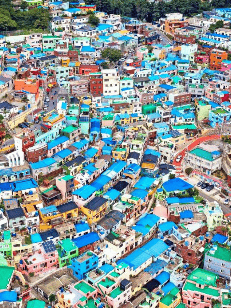 Colorful hillside houses with vibrant rooftops in a densely populated urban neighborhood.