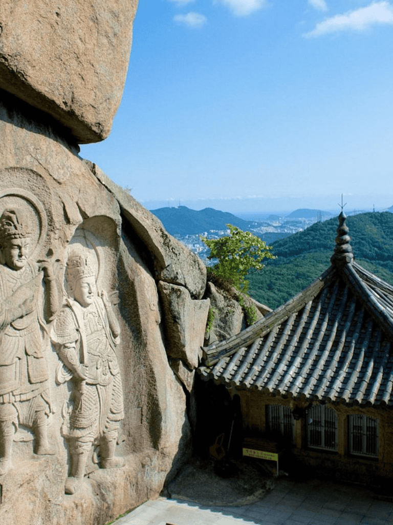Ancient stone carvings overlooking scenic mountain view in Korea.