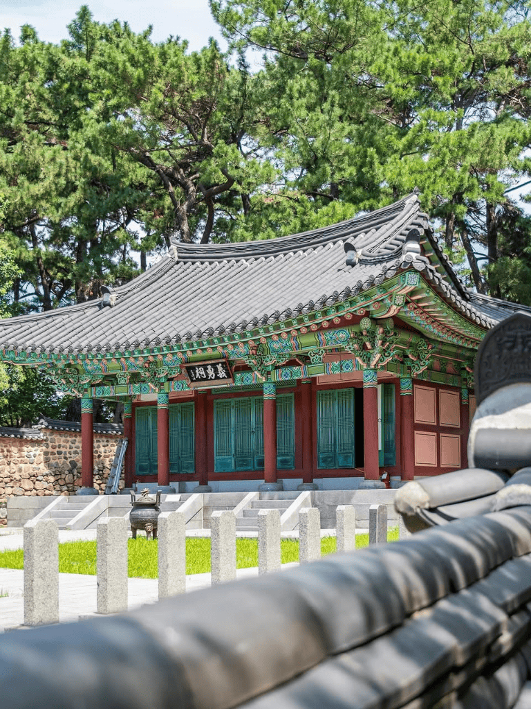 Intricate traditional Korean temple surrounded by lush green trees at Quest For Directions site.