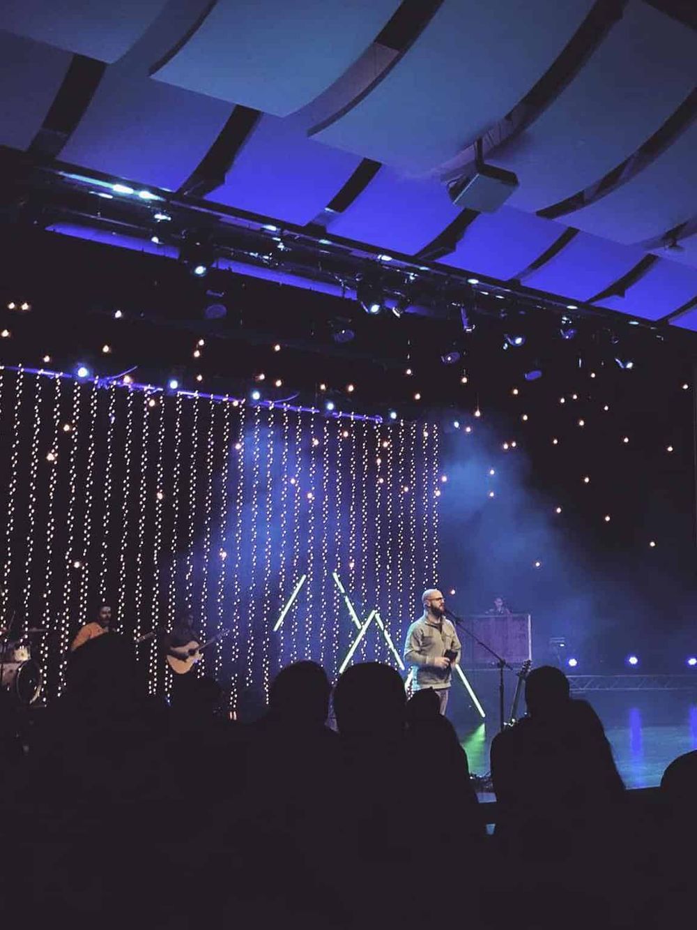 Bright stage with musicians performing under colorful lighting at QuestForDirections event.