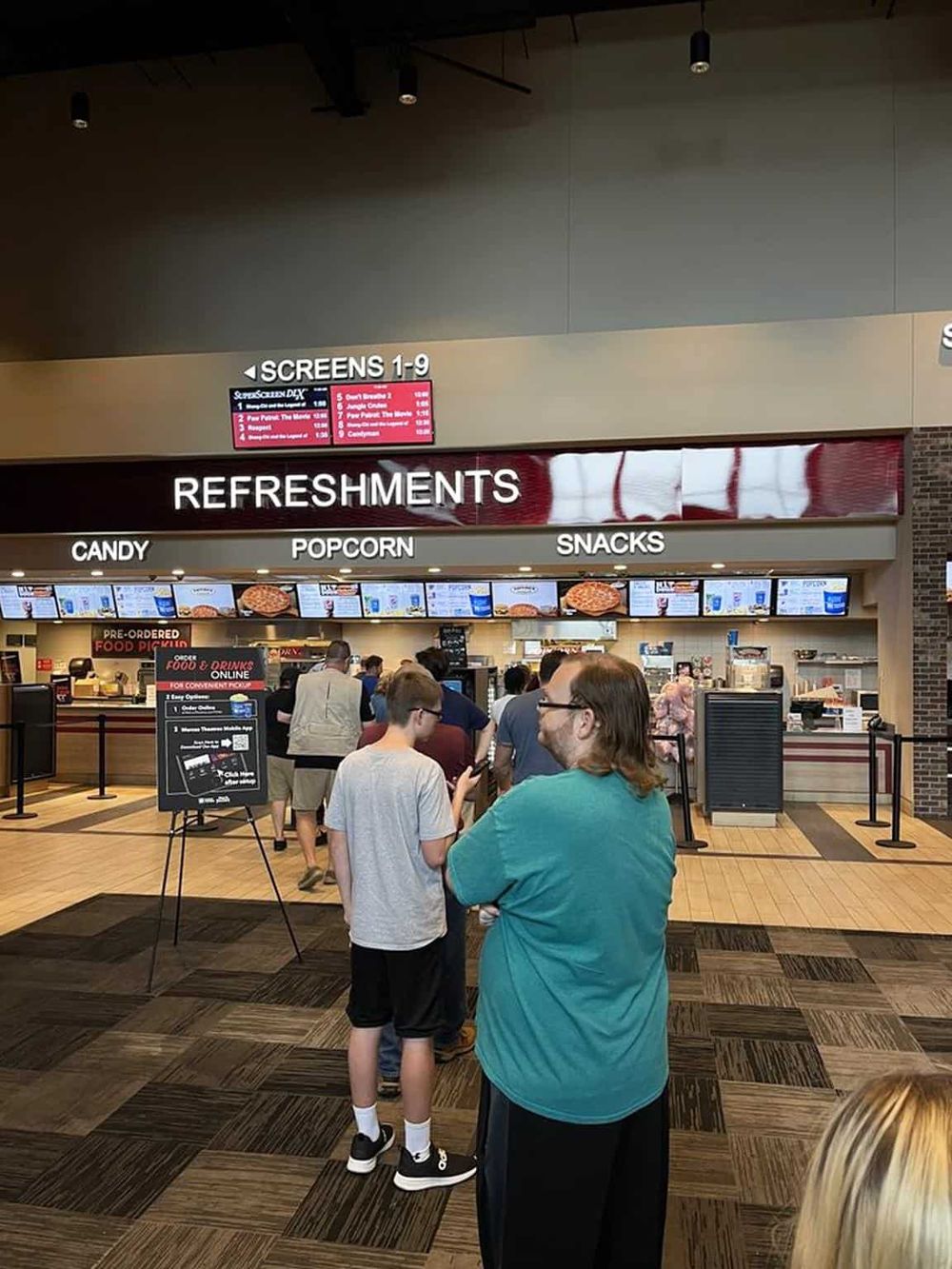 Online fast food ordering and pickup, digital menu screens, queue at restaurant counter.