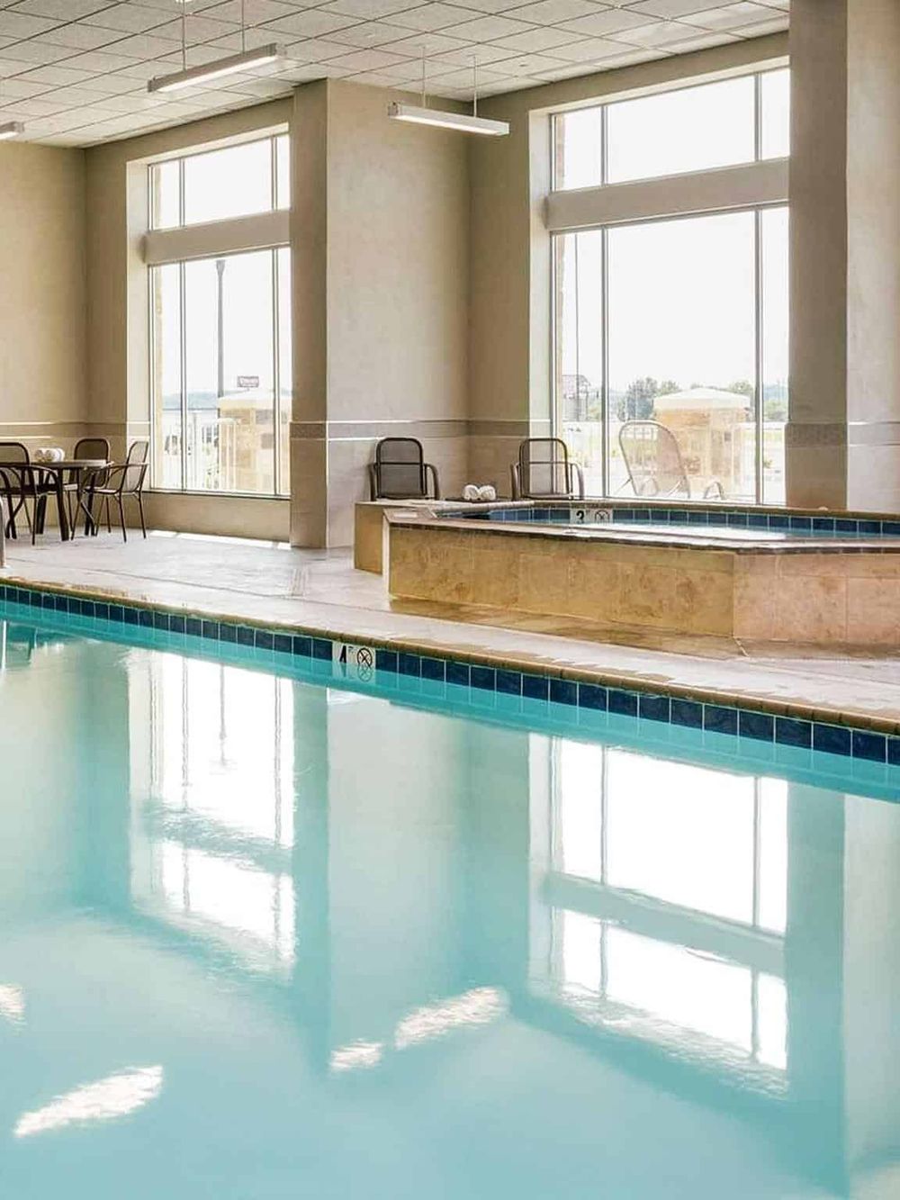 Indoor hotel pool with large windows providing natural light and city views.