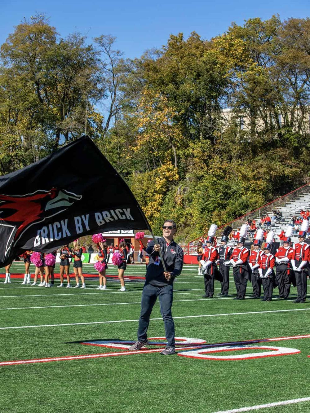 Vibrant high school band and cheerleaders on football field celebrating during game day.