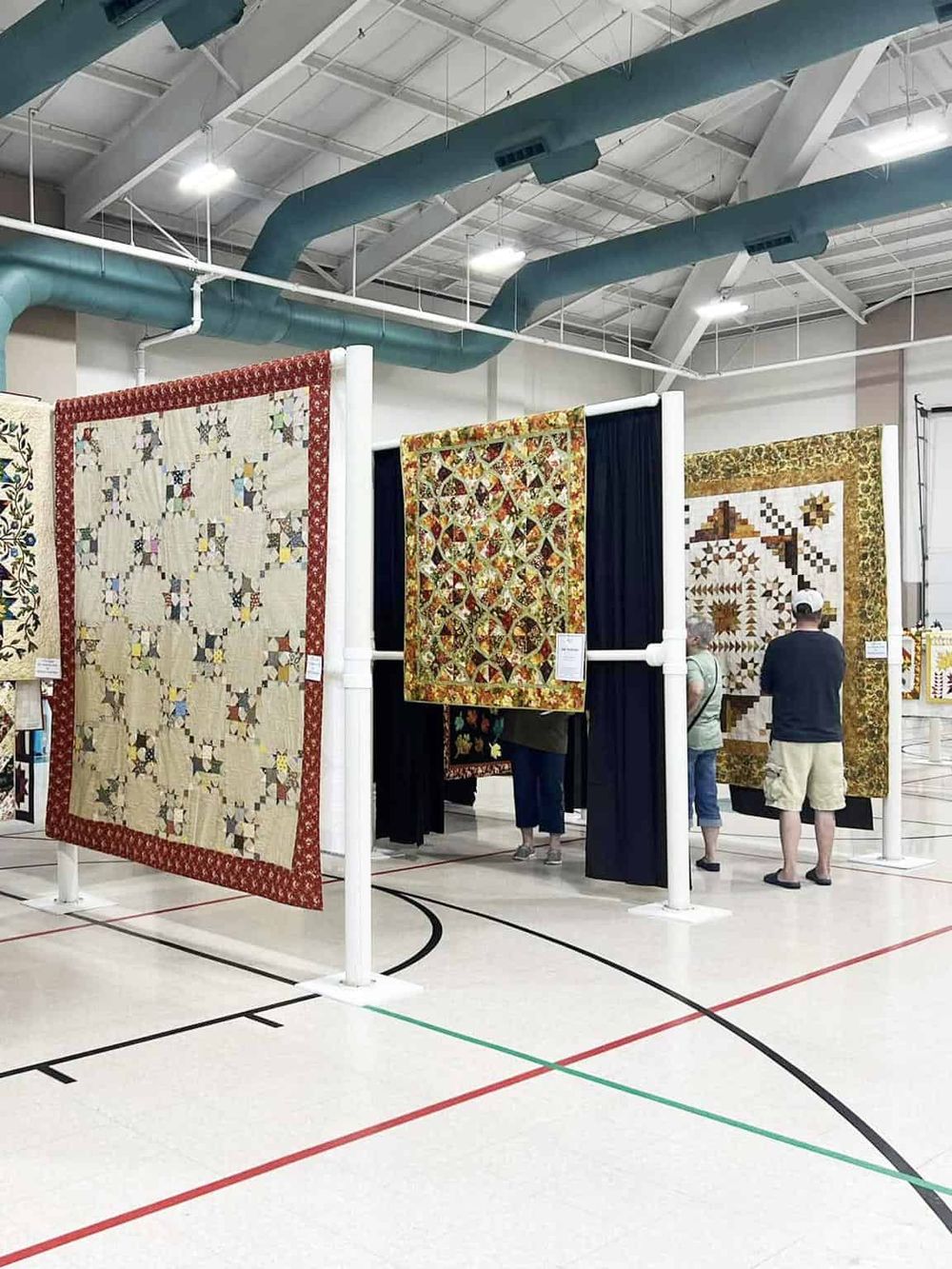 Colorful quilts on display at an indoor quilt show exhibition for quilt enthusiasts.