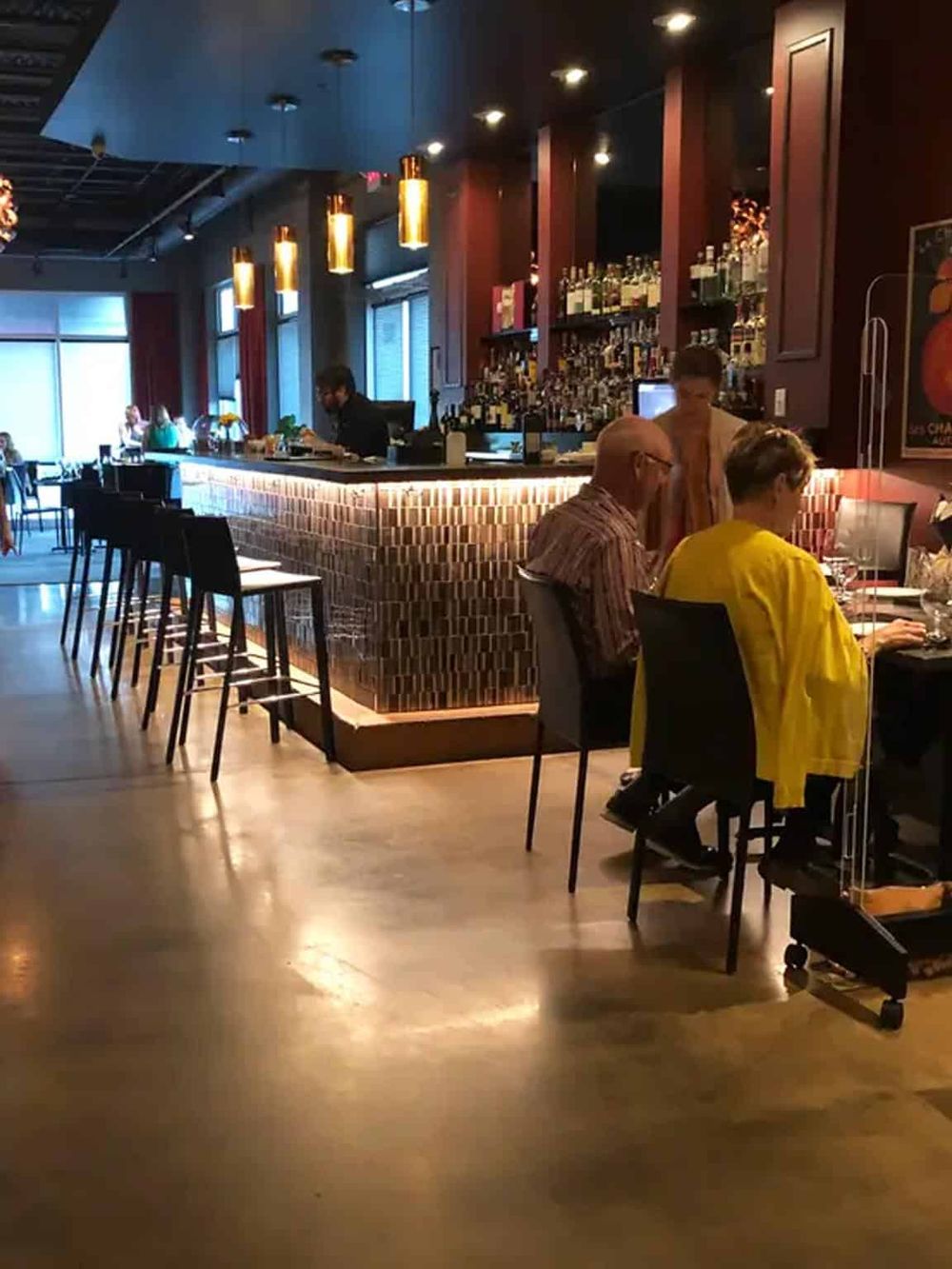 Stylish bar interior with seating, modern lighting, and a well-stocked liquor display, perfect for a nightlife experience.