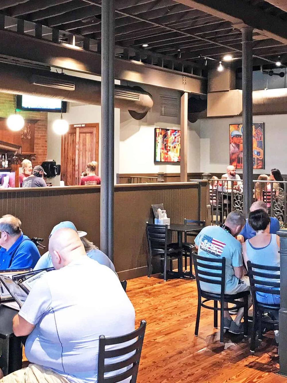 Comfortable American restaurant interior with patrons dining and colorful artwork on walls.