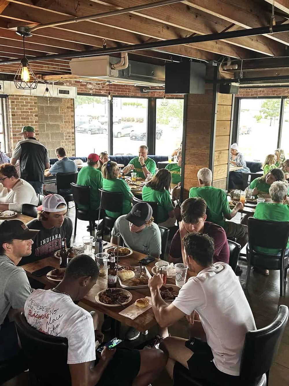 Lively sports bar with customers enjoying food and drinks in a rustic interior.