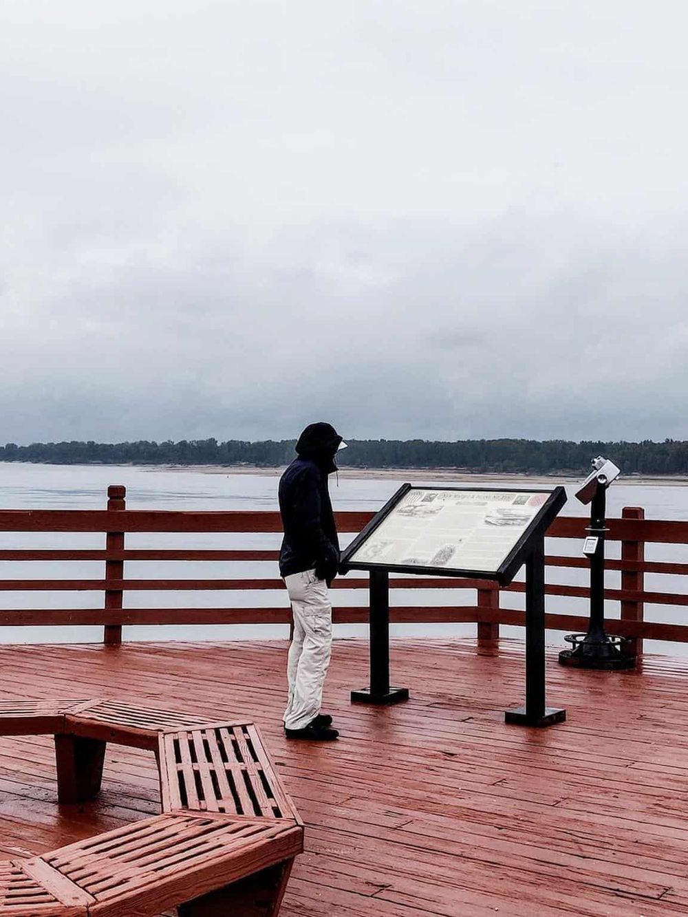 Seafarer viewing information board at scenic riverside observation deck.