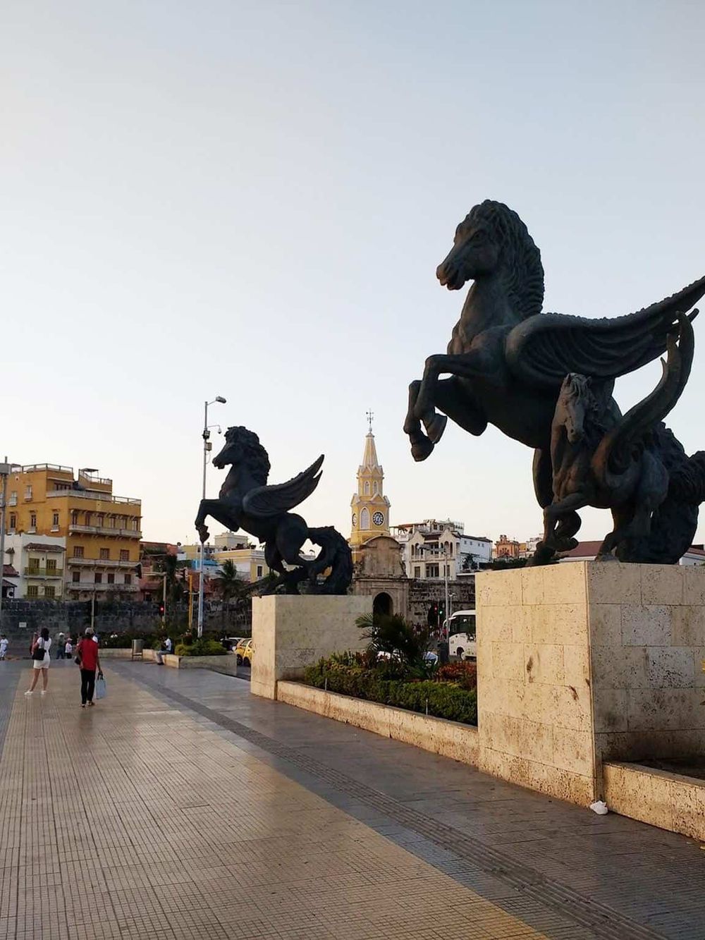 Bronze Pegasus sculptures on a city sidewalk in quest for directions, highlighting architectural and artistic travel landmarks.