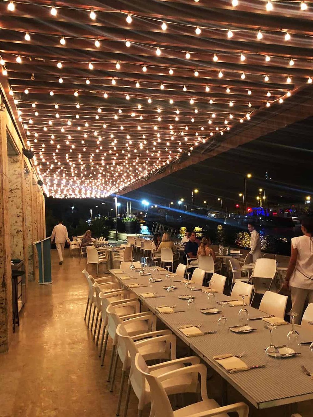Outdoor dining under string lights at QuestForDirections waterfront restaurant.