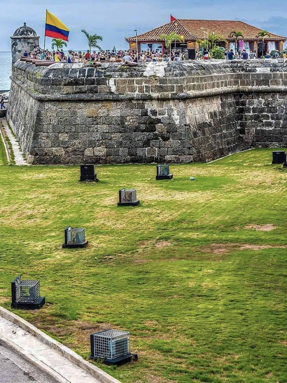 Ancient fortress with lush green lawn, balloons traps, and a lively event under a clear sky.