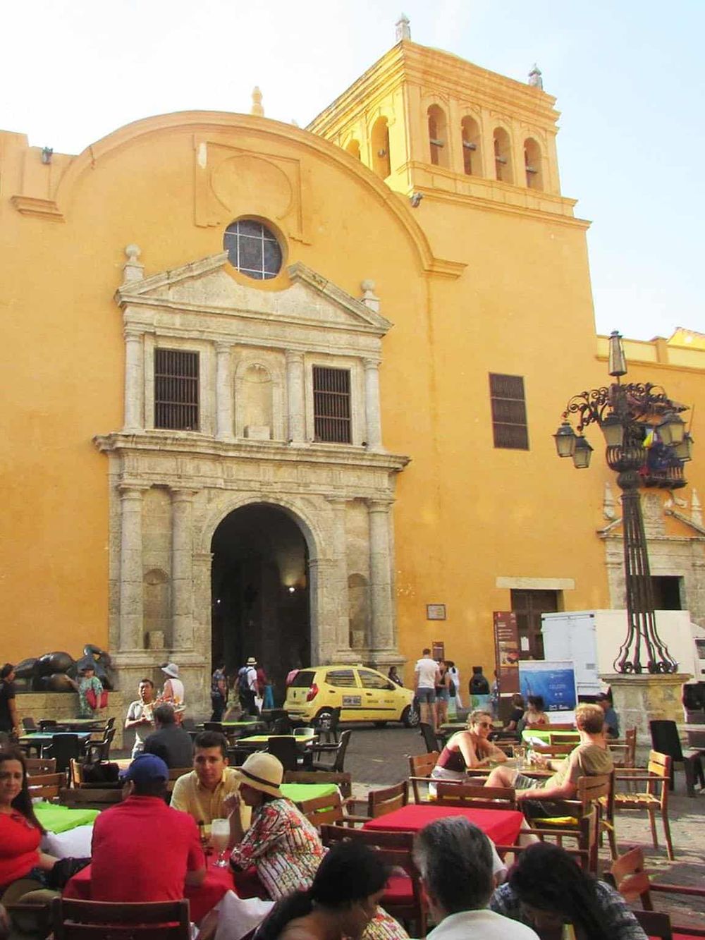 Colorful outdoor café in front of historic yellow church, popular tourist spot in Mexico City.