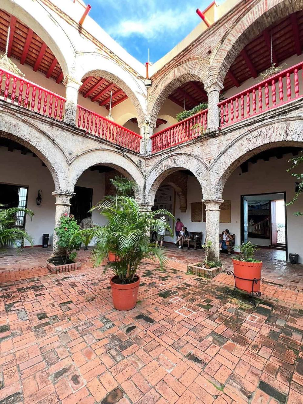 Colorful historic Spanish colonial architecture with red accents and lush potted plants.