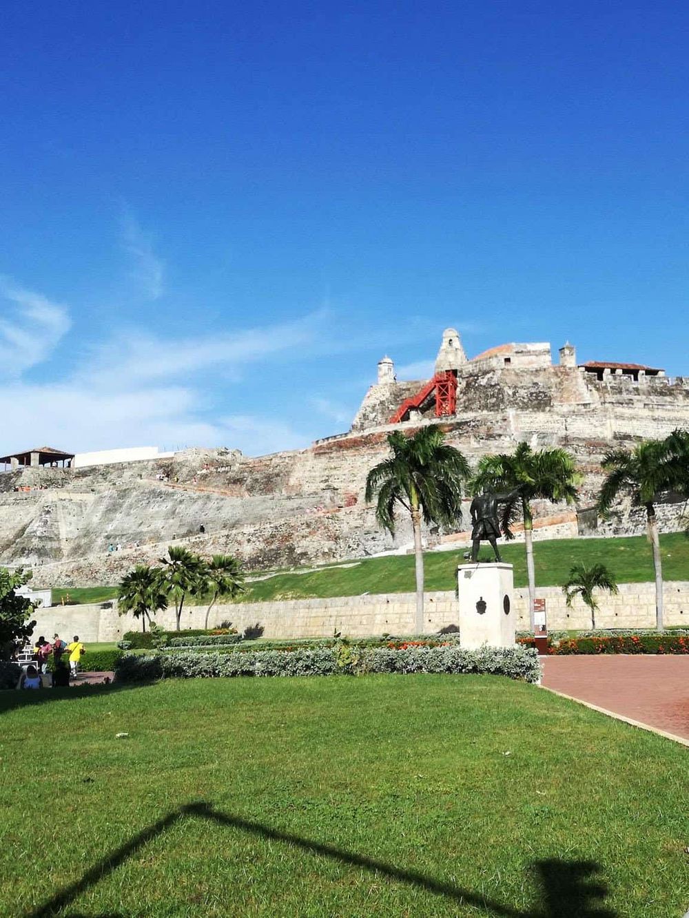 Historic Fort in San Juan, Puerto Rico, with lush green park and palm trees under bright blue sky.