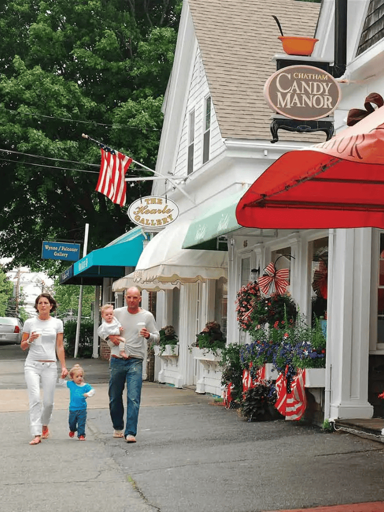 Chatham Candy Manor storefront with patriotic decorations and visitors in a quaint downtown area.
