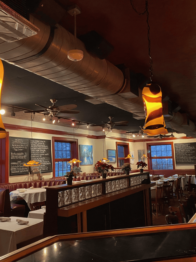 Cozy restaurant interior with warm lighting, wooden accents, and festive holiday decor, ideal for dining and gatherings.
