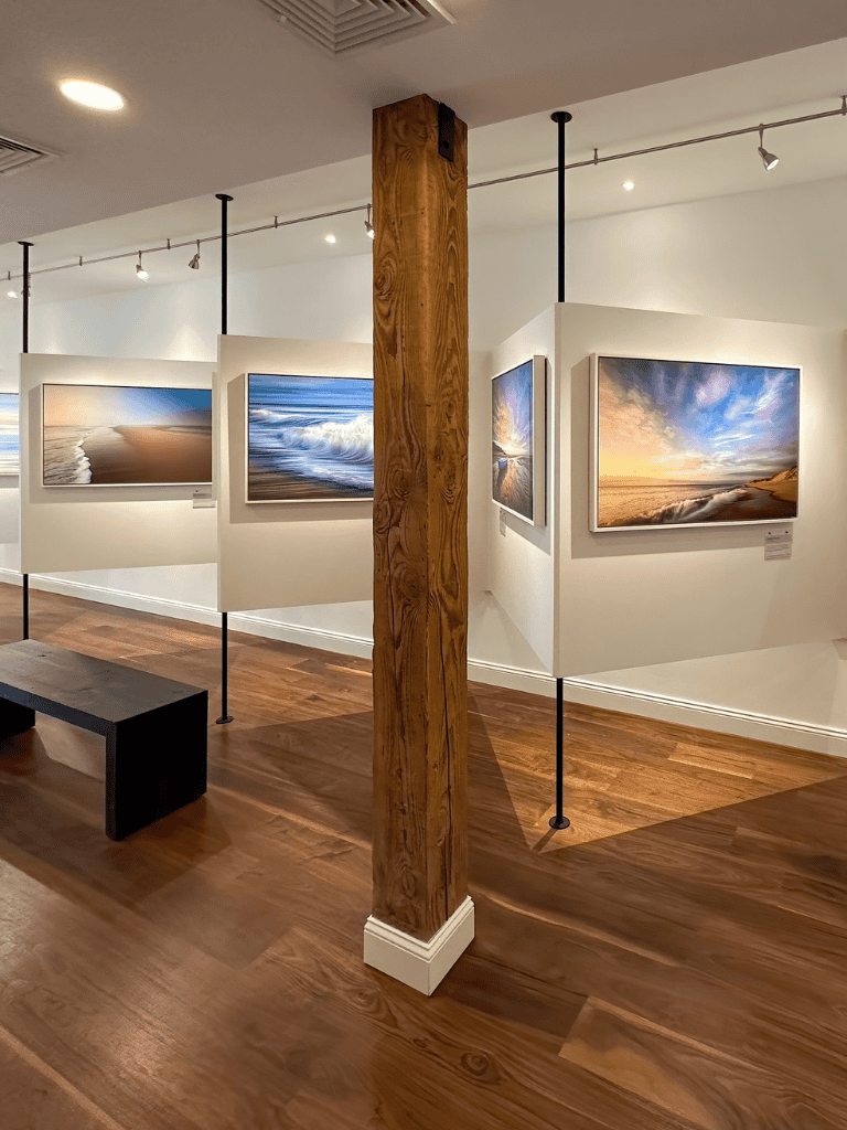 Vibrant ocean and beach landscape photography displayed in art gallery, showcasing scenic coastal artworks.